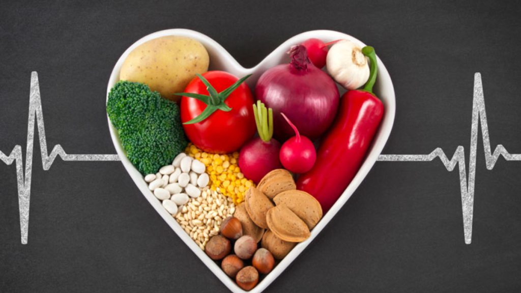 عکس یک ظرف قلبی با نماد ضربان قلب دارای پیاز و سیر و فلفل دلمه و بروکلی و سایر موارد مفید برای قلب